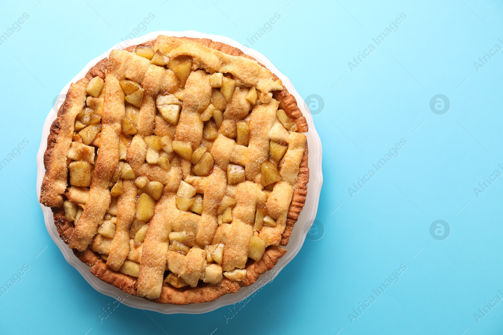 Photo of Tasty homemade apple pie on light blue background, top view. Space for text