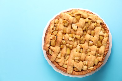 Photo of Tasty homemade apple pie on light blue background, top view. Space for text