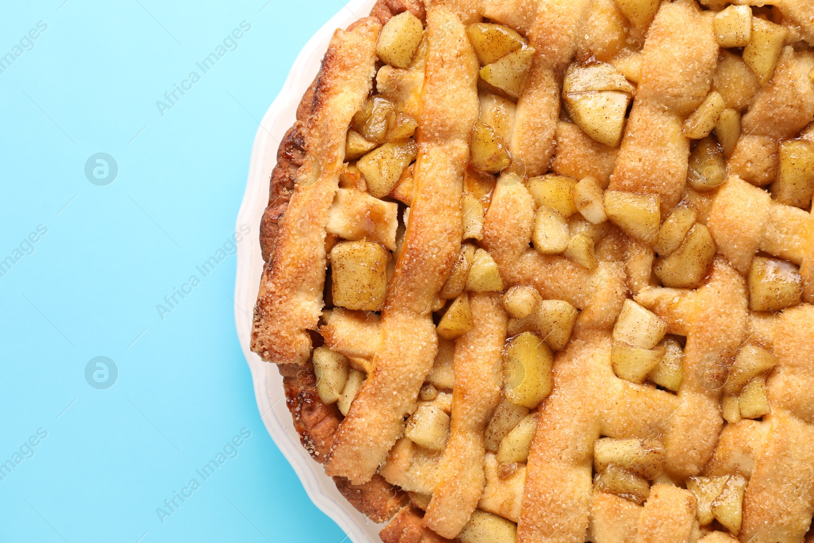 Photo of Tasty homemade apple pie on light blue background, top view. Space for text