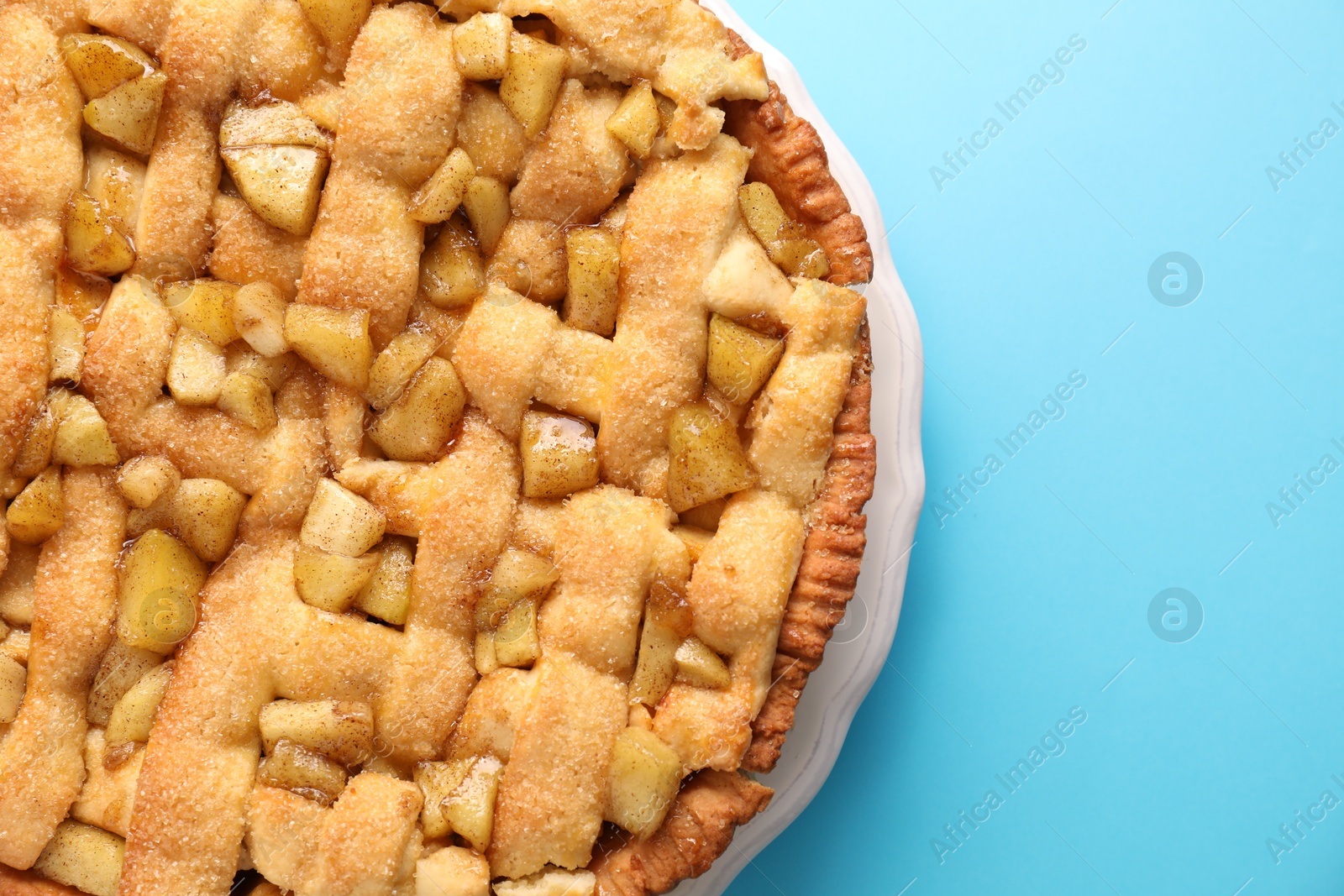 Photo of Tasty homemade apple pie on light blue background, top view. Space for text