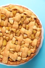 Photo of Tasty homemade apple pie on light blue background, top view