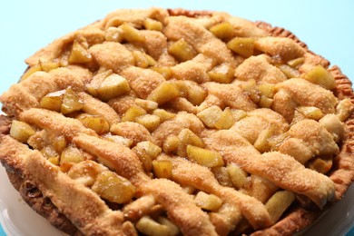 Tasty homemade apple pie on light blue background, closeup