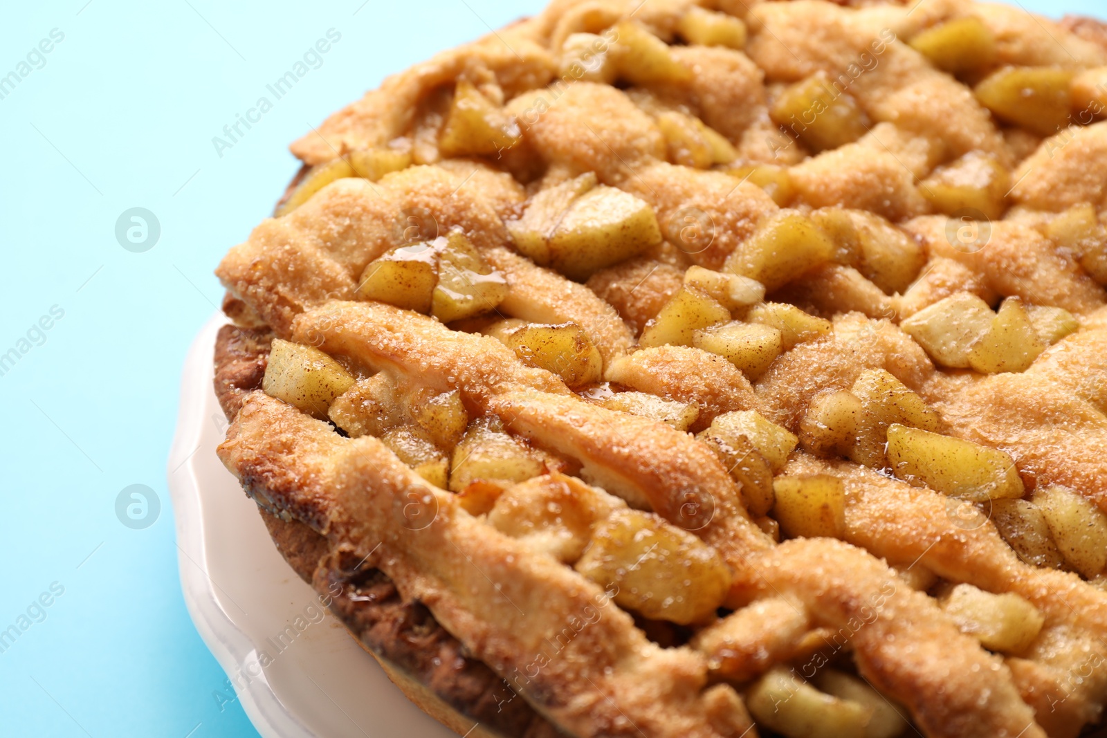 Photo of Tasty homemade apple pie on light blue background, closeup