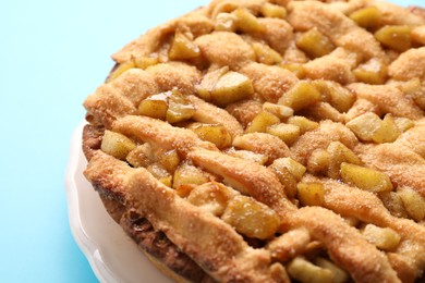 Tasty homemade apple pie on light blue background, closeup