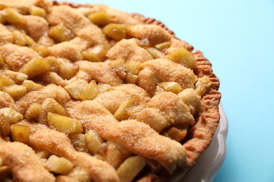 Photo of Tasty homemade apple pie on light blue background, closeup