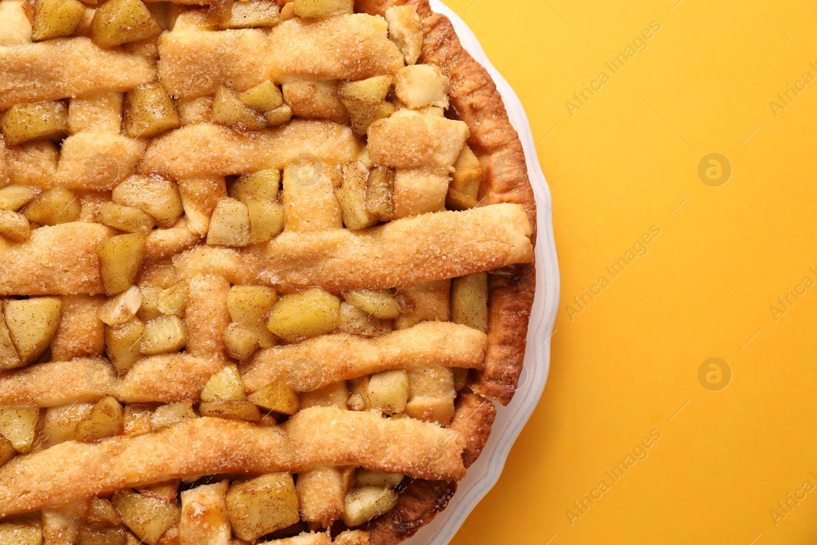 Photo of Tasty homemade apple pie on yellow background, top view. Space for text