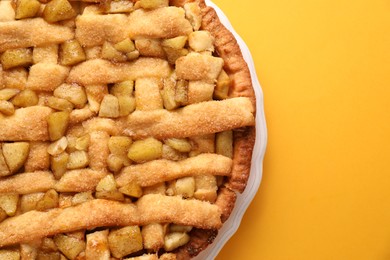 Photo of Tasty homemade apple pie on yellow background, top view. Space for text