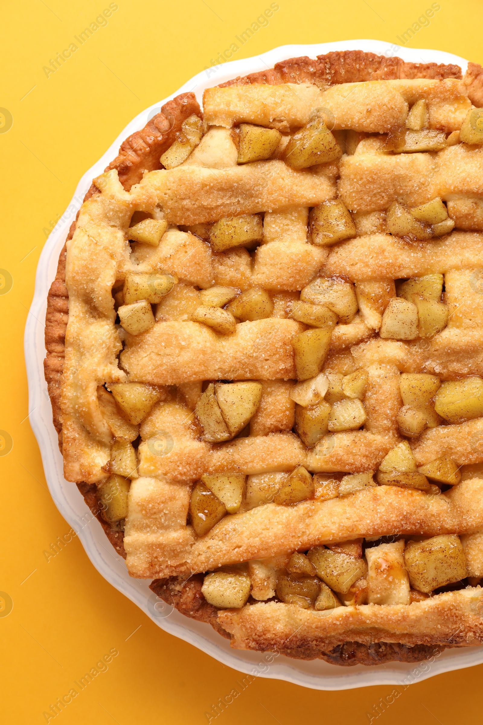 Photo of Tasty homemade apple pie on yellow background, top view