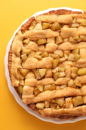 Photo of Tasty homemade apple pie on yellow background, top view