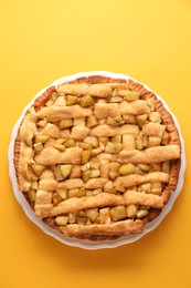 Tasty homemade apple pie on yellow background, top view