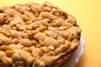 Photo of Tasty homemade apple pie on yellow background, closeup