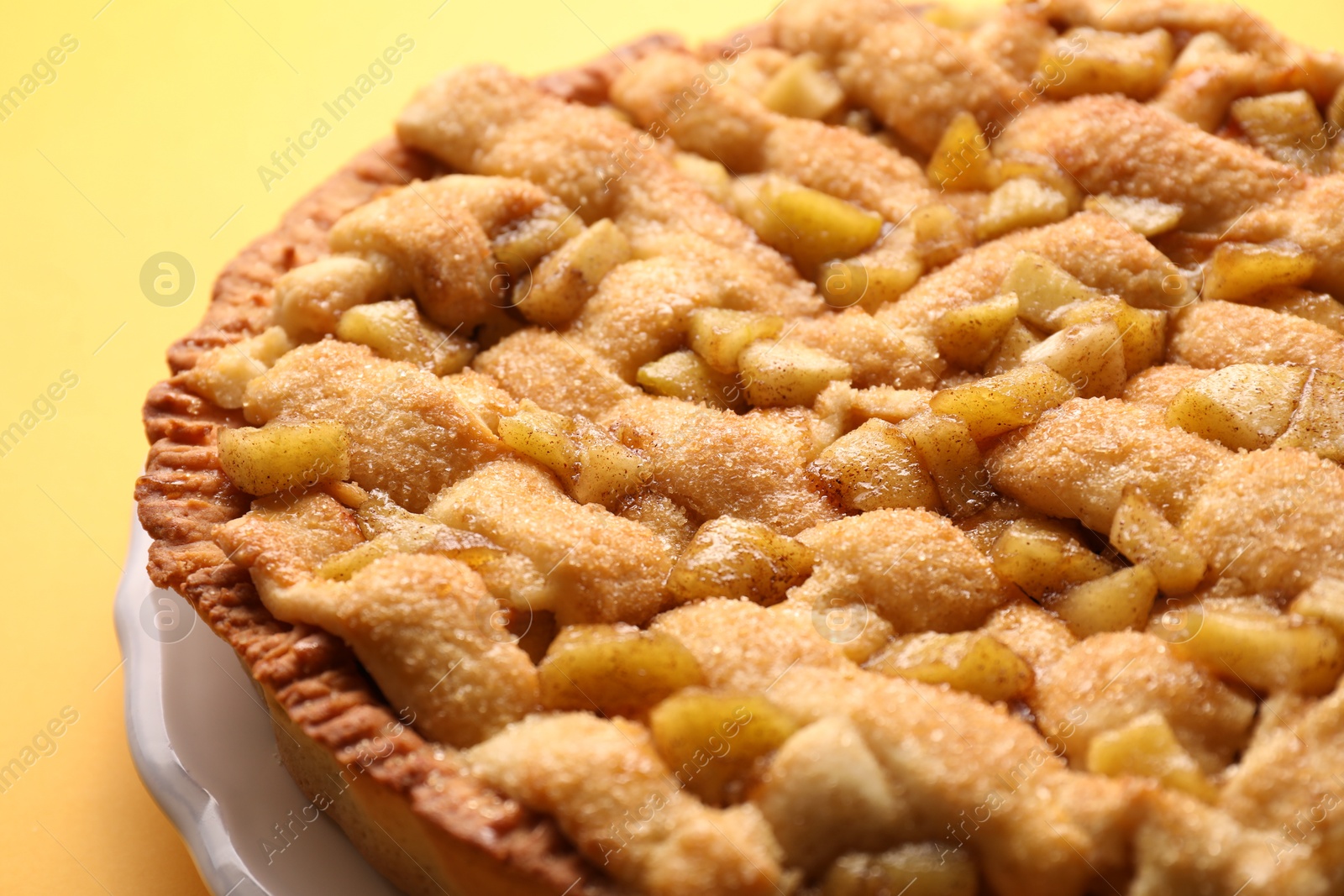 Photo of Tasty homemade apple pie on yellow background, closeup