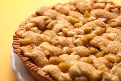 Tasty homemade apple pie on yellow background, closeup