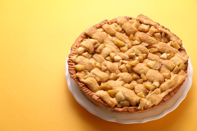 Photo of Tasty homemade apple pie on yellow background. Space for text