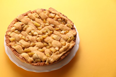 Photo of Tasty homemade apple pie on yellow background. Space for text