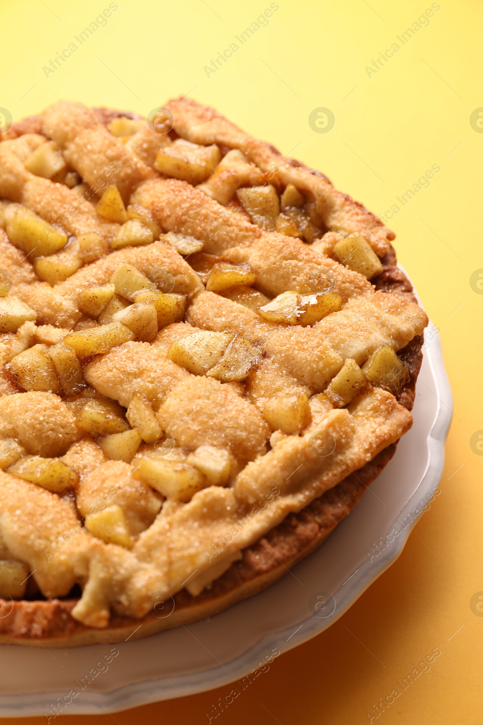 Photo of Tasty homemade apple pie on yellow background, closeup