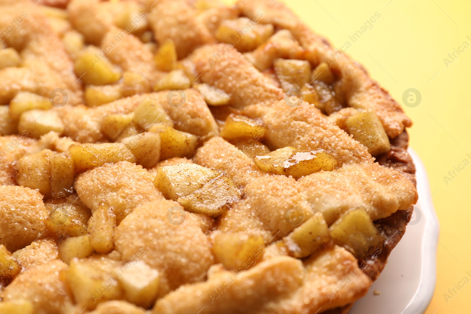 Photo of Tasty homemade apple pie on yellow background, closeup