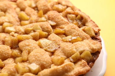 Tasty homemade apple pie on yellow background, closeup