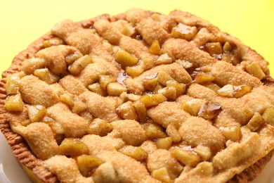 Photo of Tasty homemade apple pie on yellow background, closeup