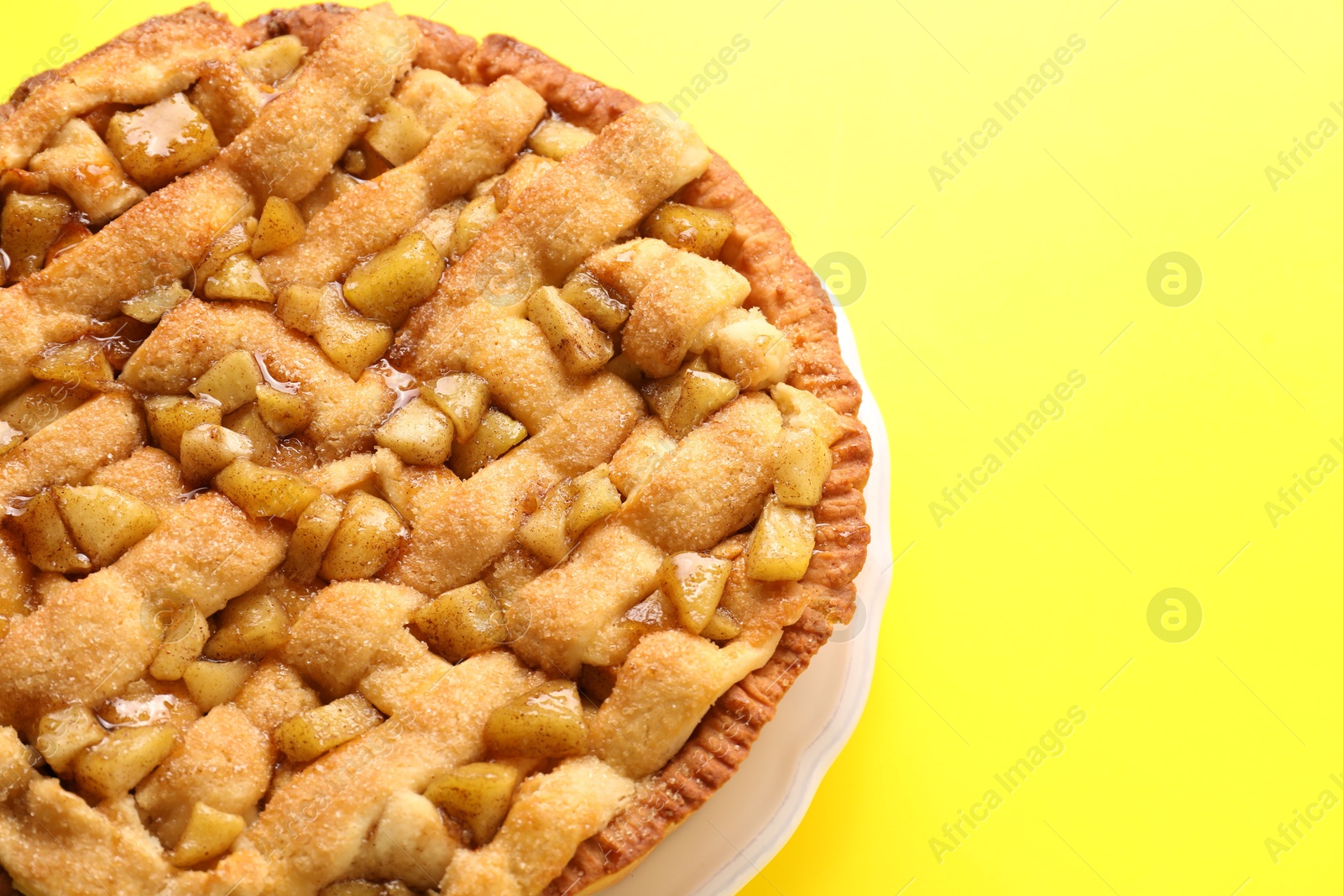 Photo of Tasty homemade apple pie on yellow background, above view. Space for text