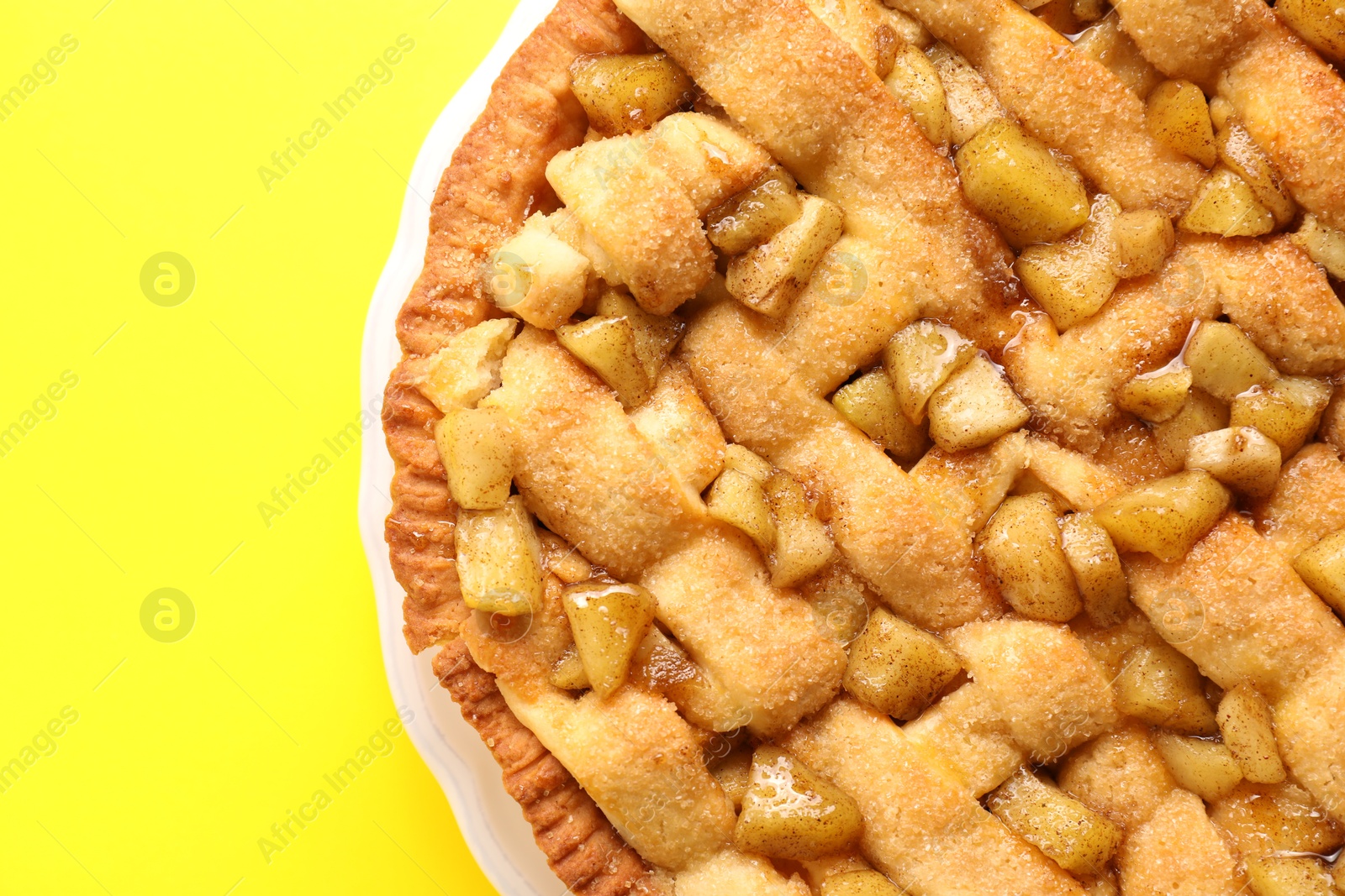 Photo of Tasty homemade apple pie on yellow background, top view. Space for text