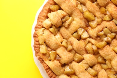 Tasty homemade apple pie on yellow background, top view. Space for text