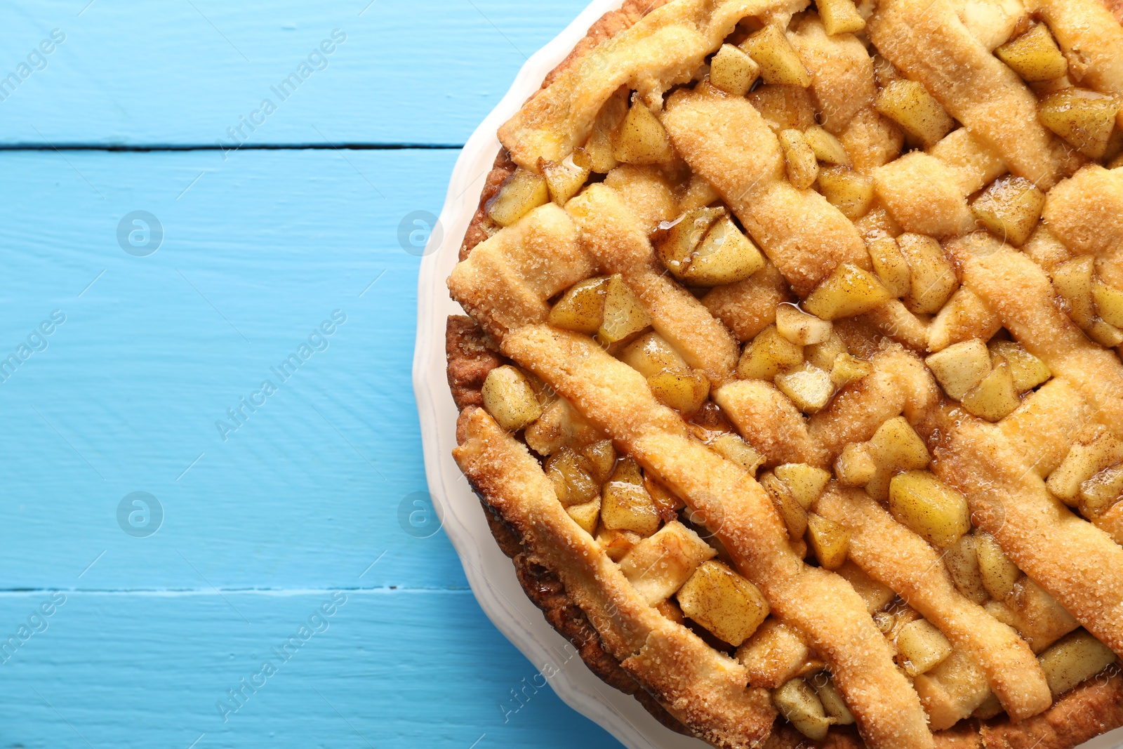 Photo of Tasty homemade apple pie on light blue wooden table, top view. Space for text