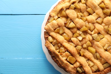 Photo of Tasty homemade apple pie on light blue wooden table, top view. Space for text