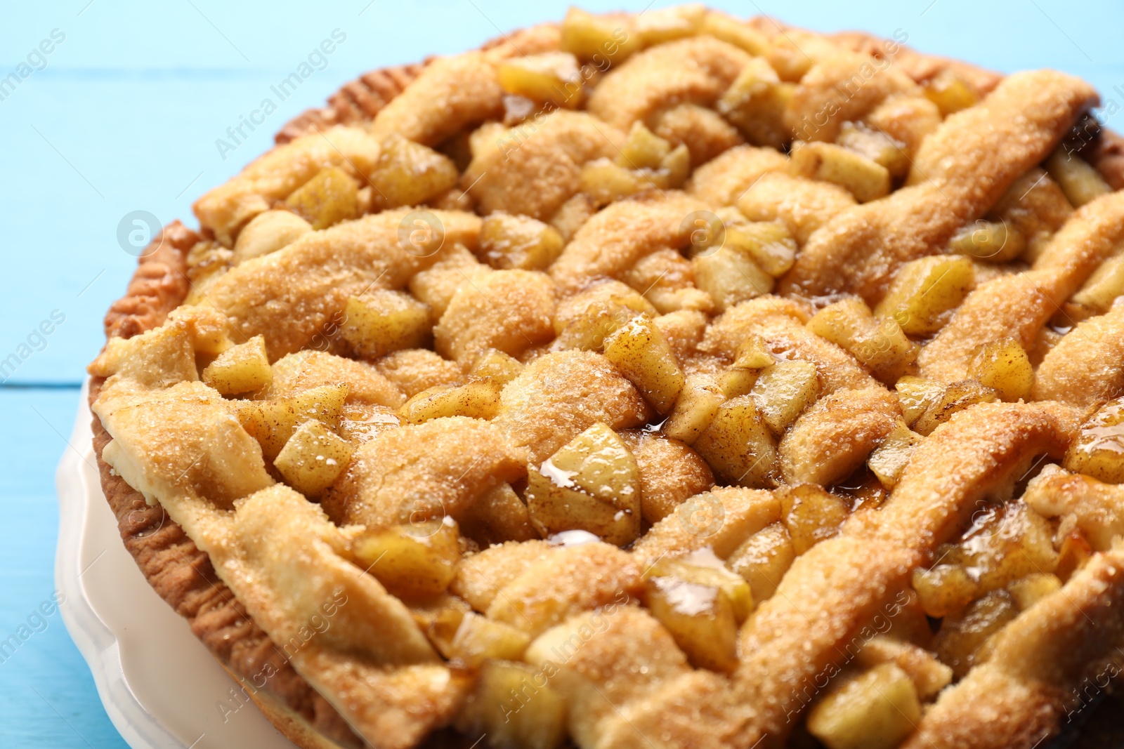 Photo of Tasty homemade apple pie on light blue table, closeup