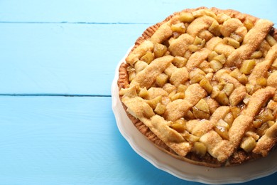 Photo of Tasty homemade apple pie on light blue wooden table. Space for text