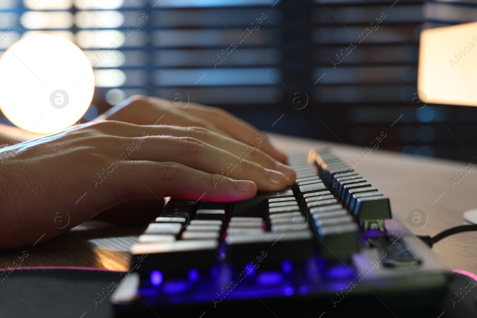 Photo of Young man using computer keyboard at wooden table indoors, closeup