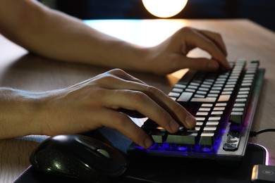 Photo of Young man using computer keyboard at wooden table indoors, closeup