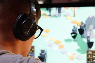 Young man playing video game at table indoors, closeup