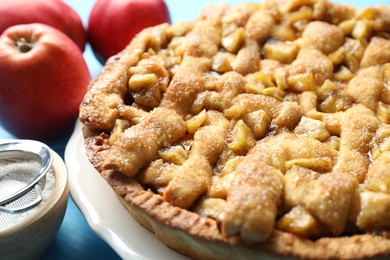 Homemade apple pie and ingredients on light blue wooden table, closeup