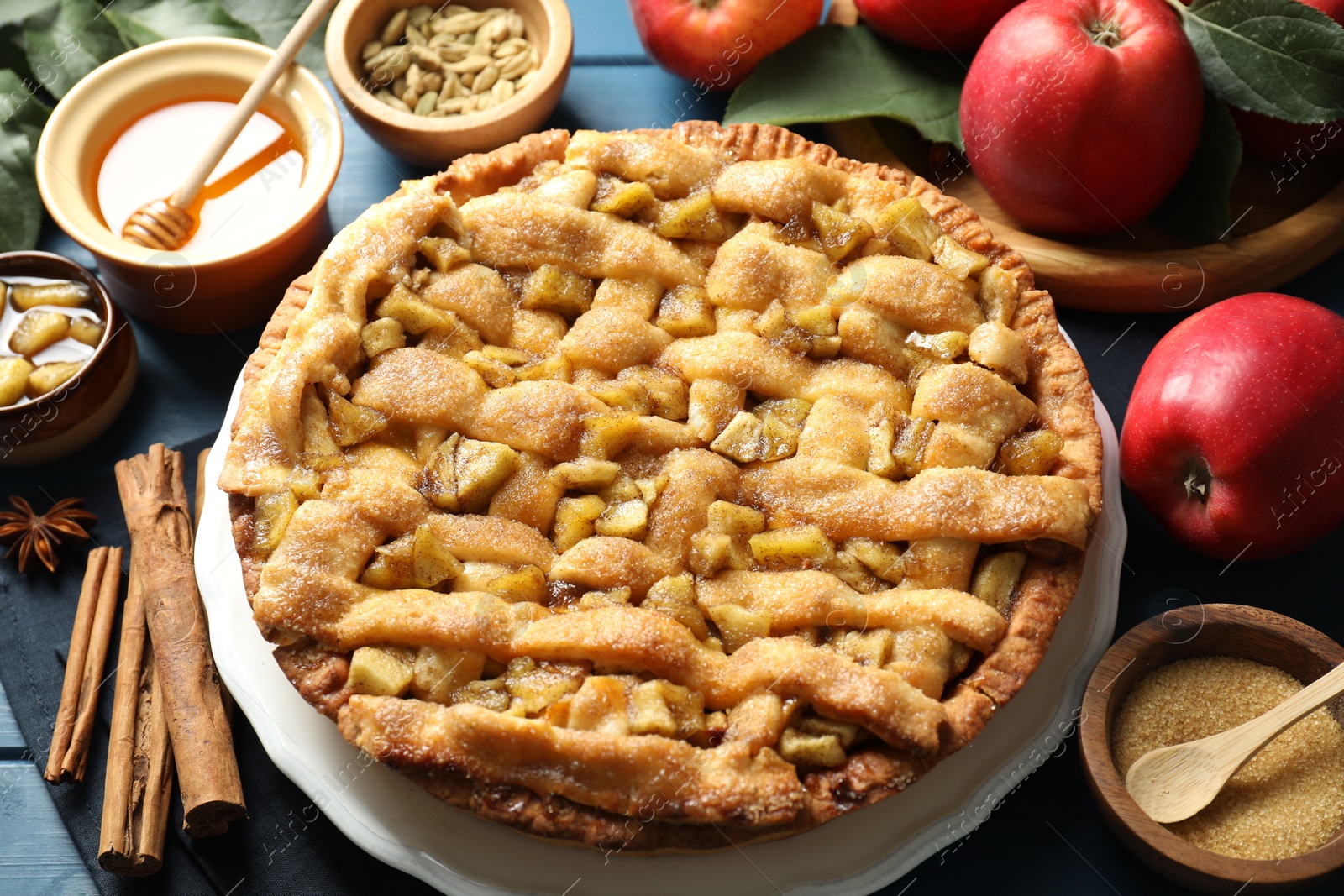 Photo of Homemade apple pie and ingredients on blue wooden table