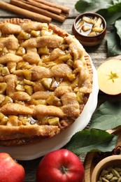 Homemade apple pie and ingredients on wooden table, closeup