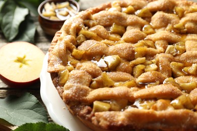 Photo of Homemade apple pie and ingredients on wooden table, closeup