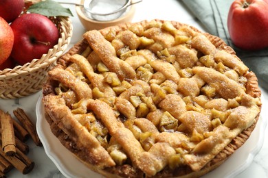 Photo of Homemade apple pie and ingredients on white marble table, closeup