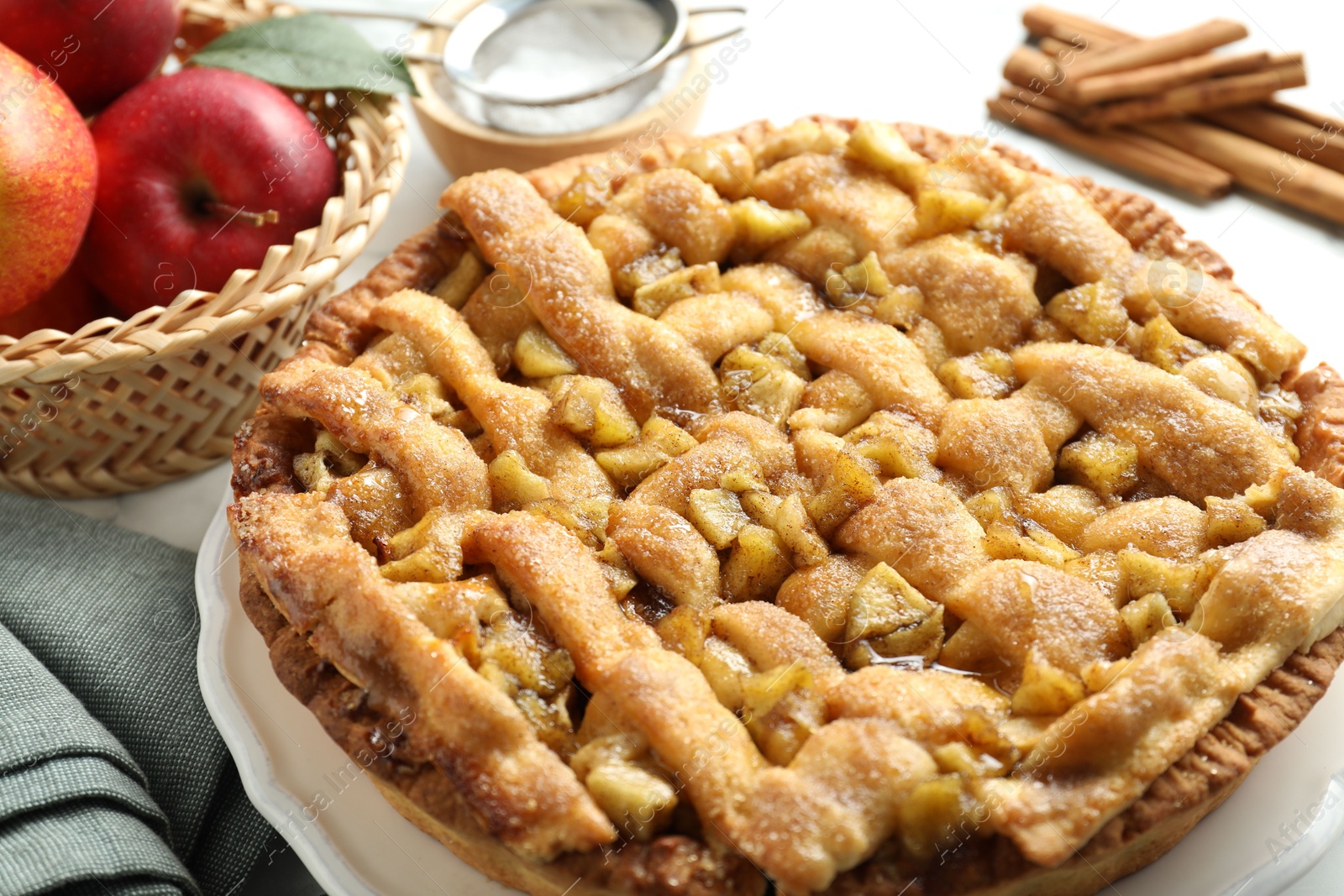 Photo of Homemade apple pie and ingredients on white marble table, closeup