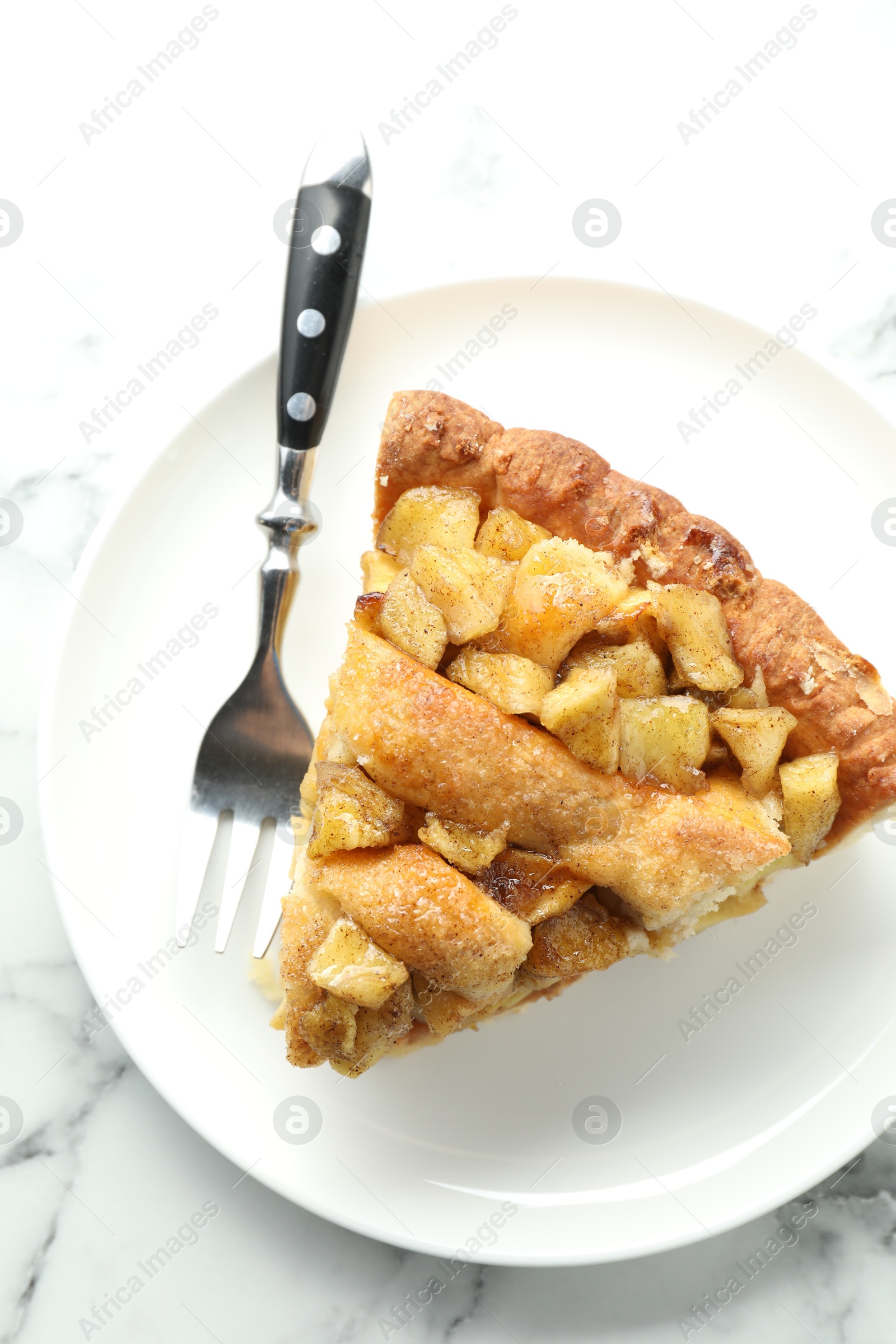 Photo of Slice of homemade apple pie and fork on white marble table, top view