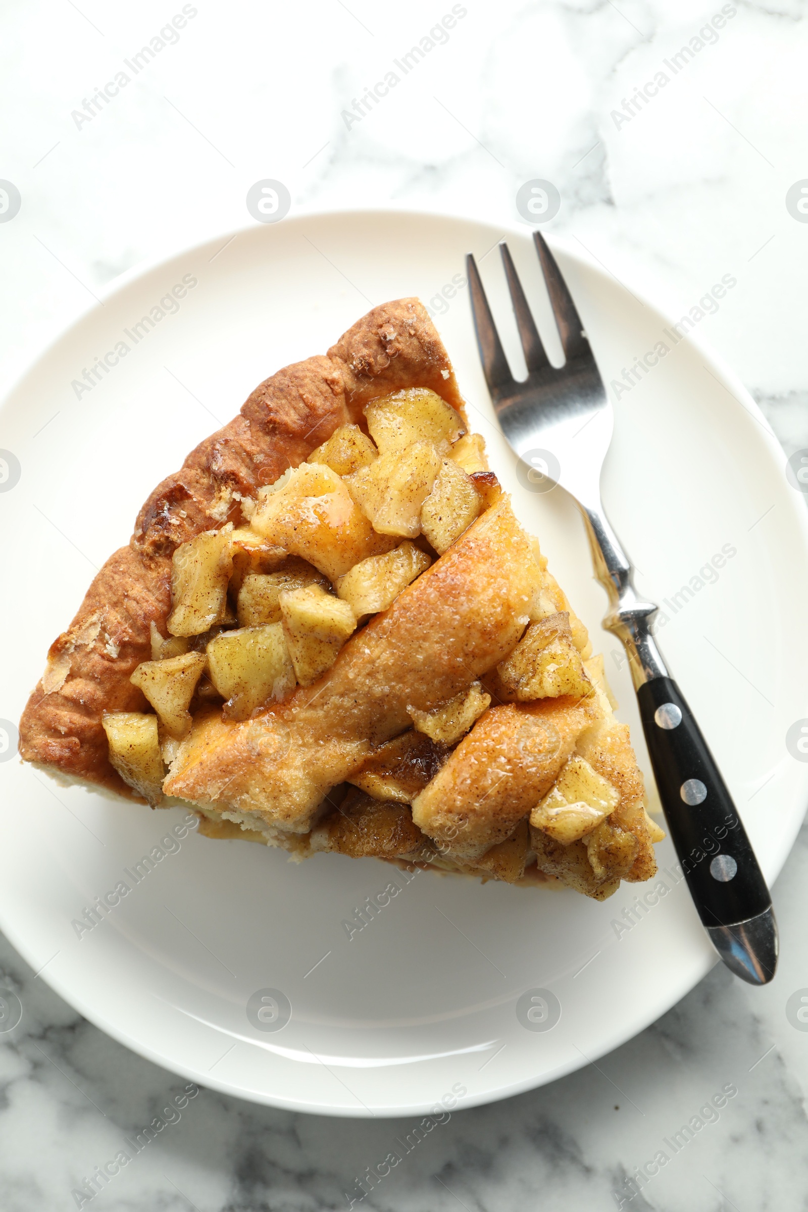 Photo of Slice of homemade apple pie and fork on white marble table, top view