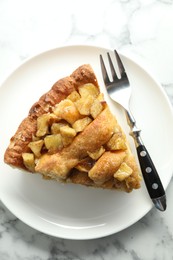 Photo of Slice of homemade apple pie and fork on white marble table, top view