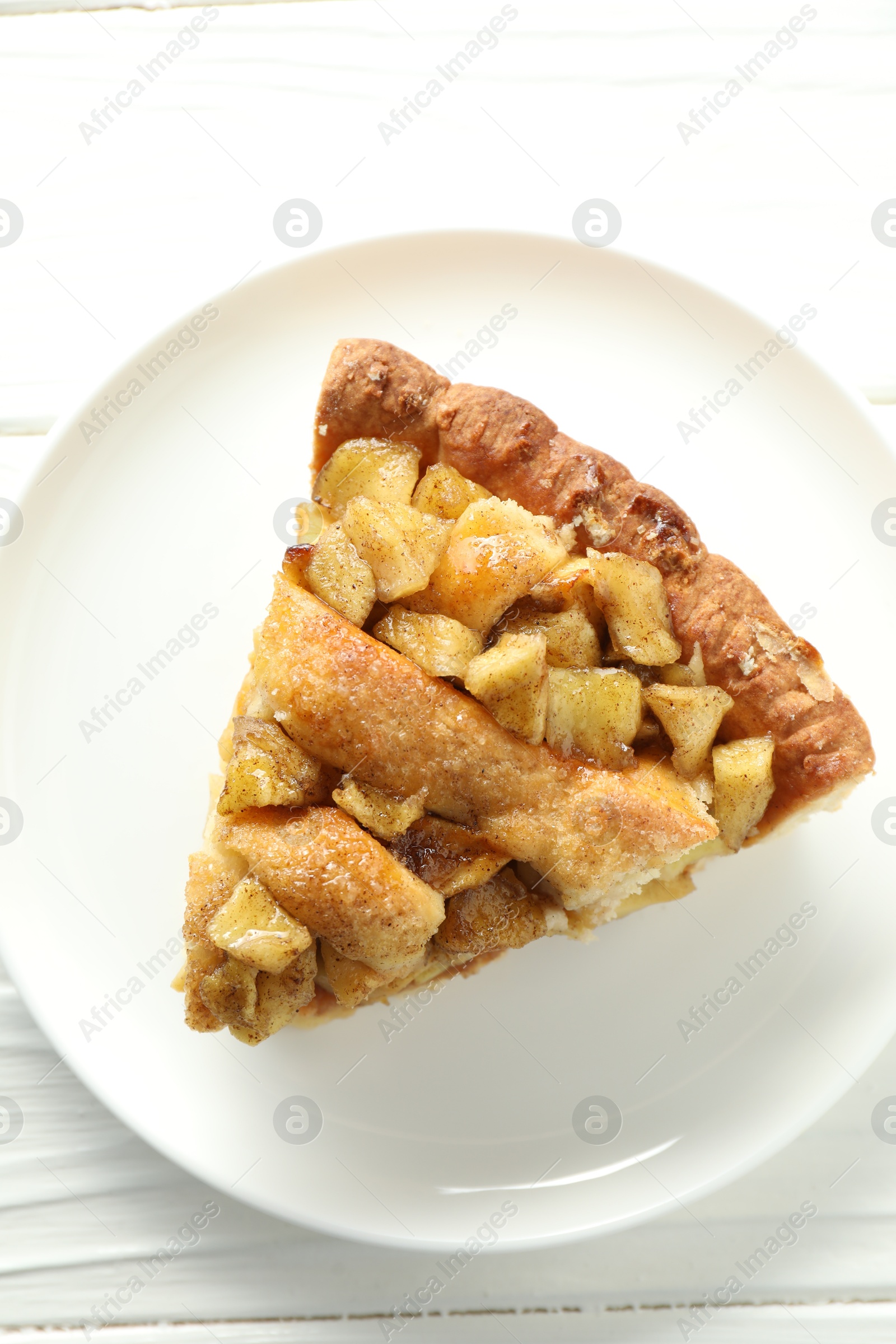 Photo of Slice of homemade apple pie on white wooden table, top view