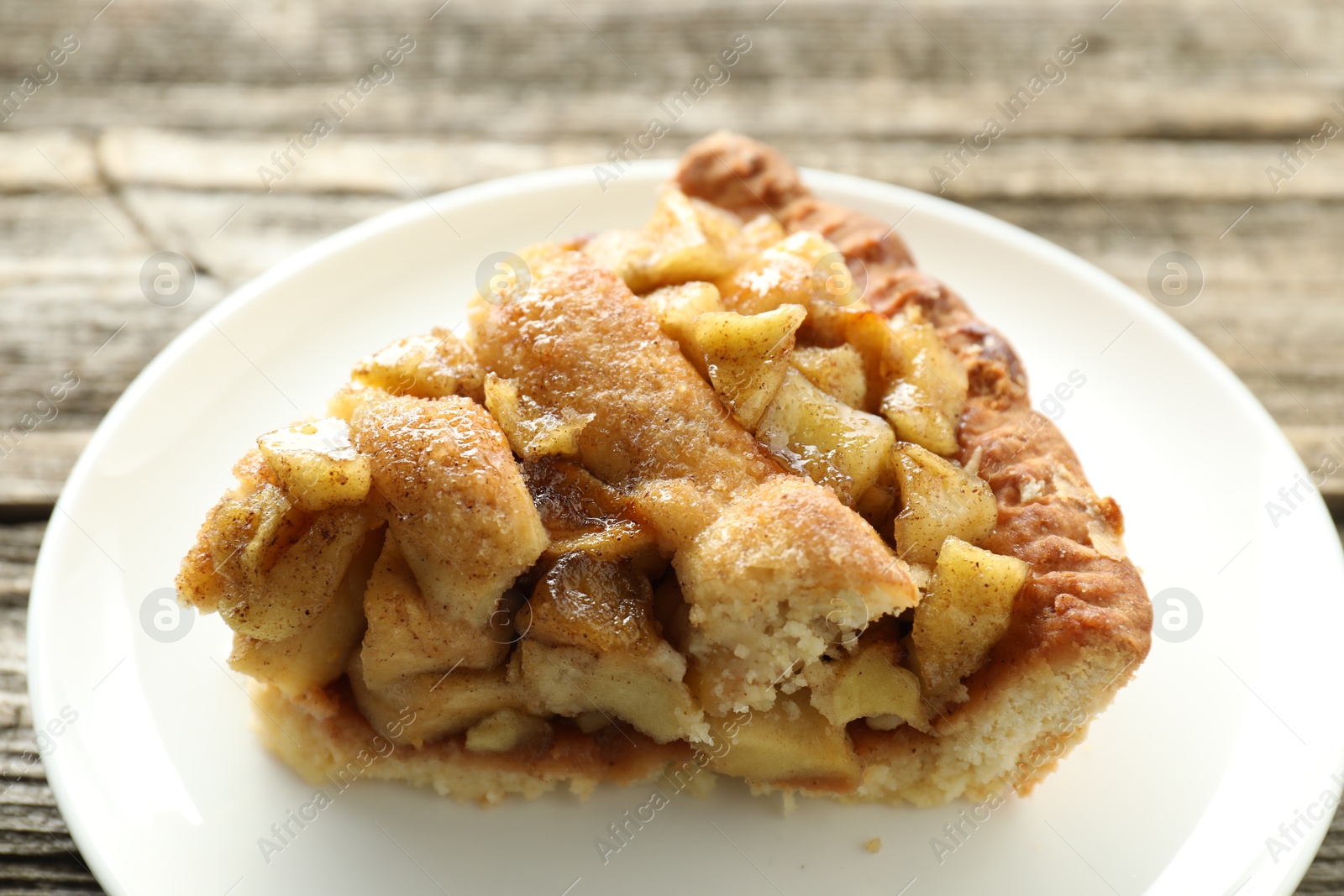 Photo of Slice of homemade apple pie on wooden table, closeup