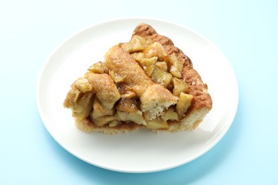 Photo of Slice of homemade apple pie on light blue background, closeup