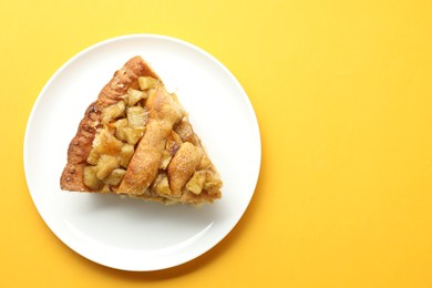 Photo of Slice of homemade apple pie on orange background, top view. Space for text