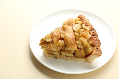 Slice of homemade apple pie on beige background, closeup