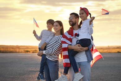 Family portrait of happy parents with children waving USA flags outdoors