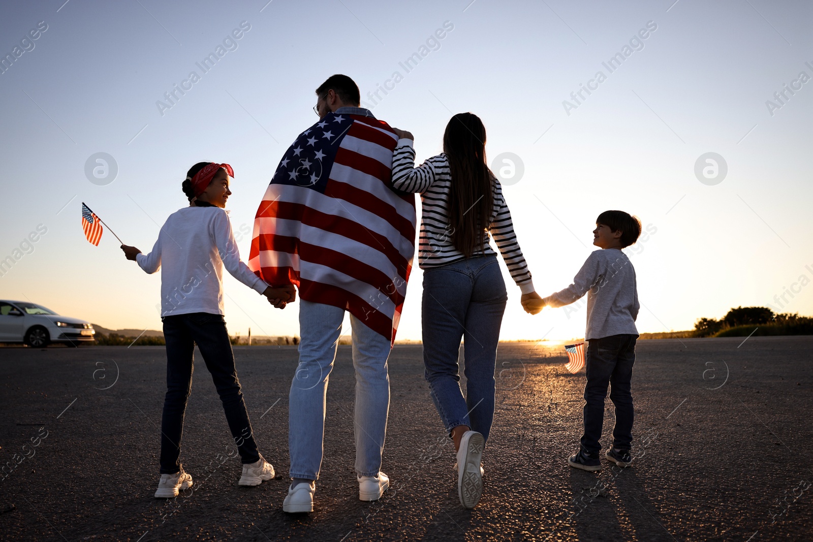 Photo of Family with flags of USA outdoors, back view