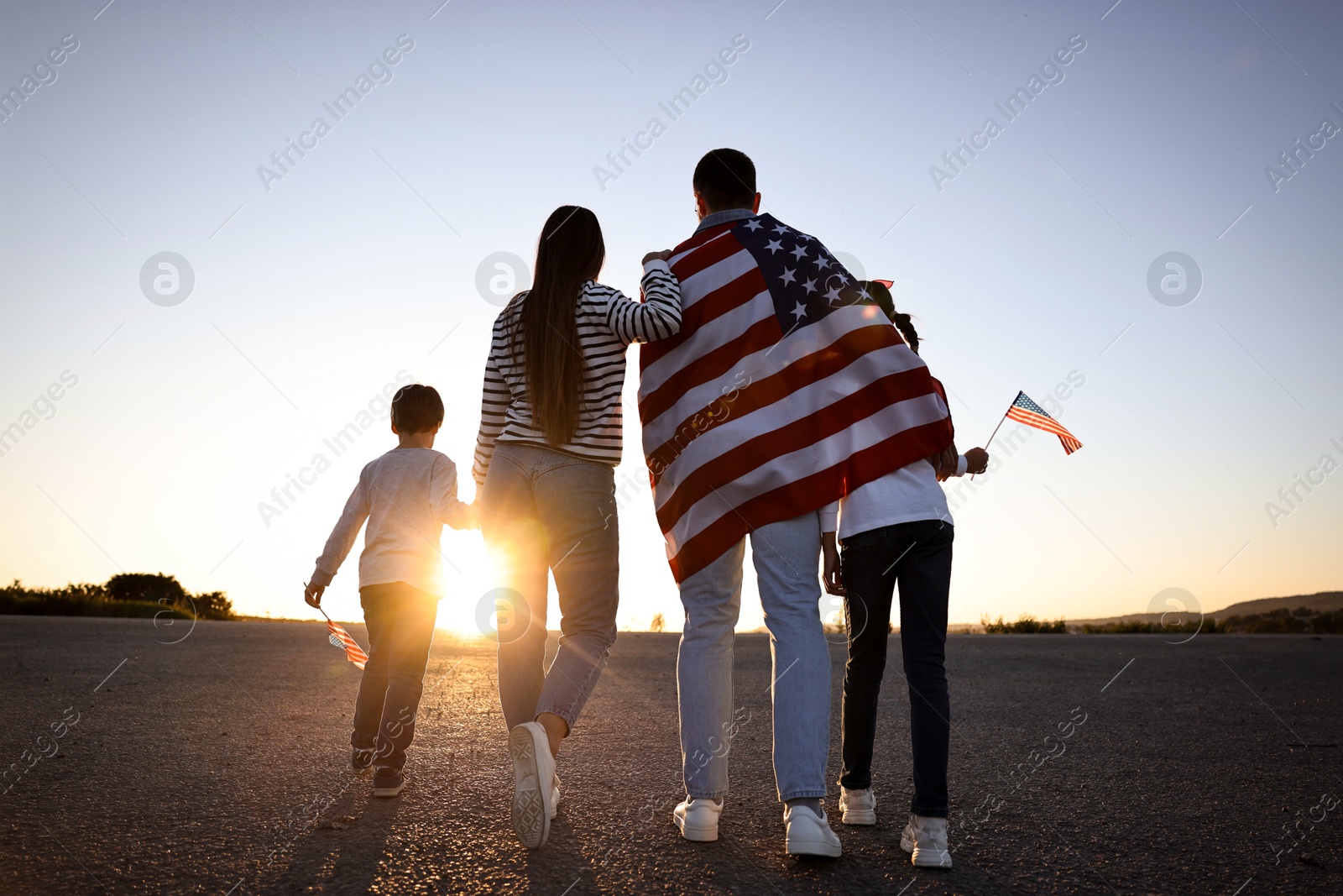 Photo of Family with flags of USA outdoors, back view